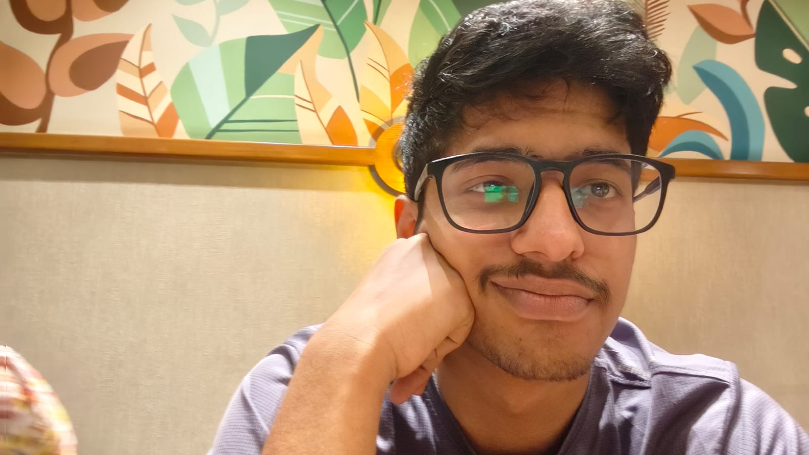 Kabir leaning on his hand wearing a purple shirt