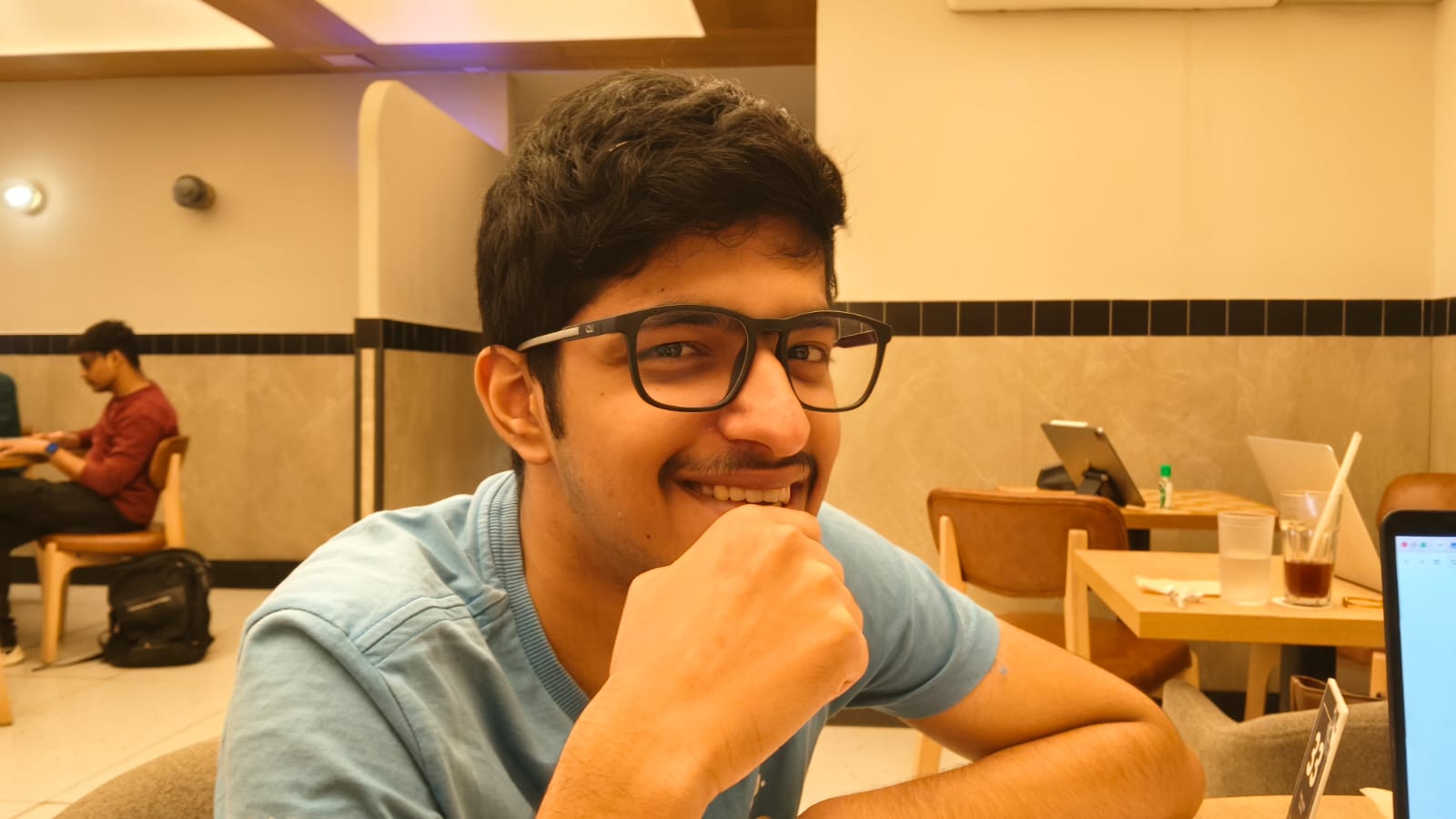 Kabir smiling at a café in a blue shirt