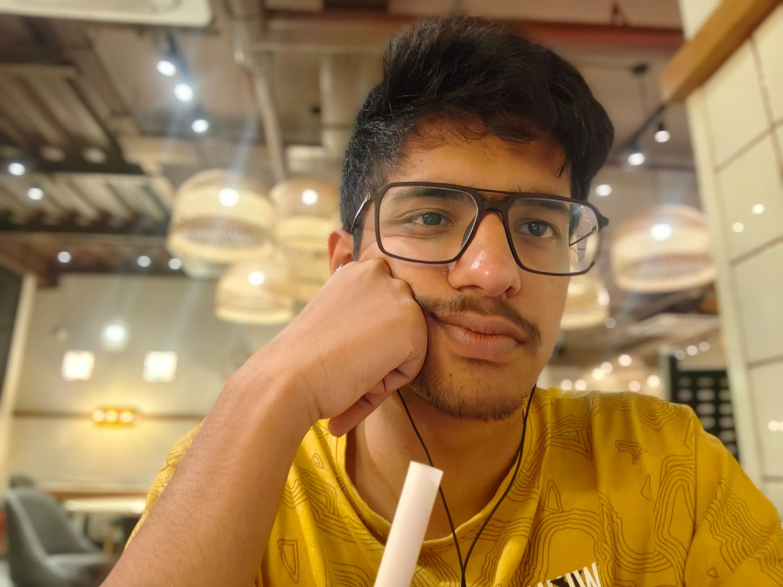 Kabir resting his face on his hand in a yellow shirt